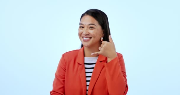 Gezicht, lach en bel me met een Aziatische vrouw die naar je wijst in de studio op een blauwe achtergrond voor communicatie. Portret, handtelefoon en gebaar met een gelukkig jongerennetwerk op haar mobiele telefoon. - Video