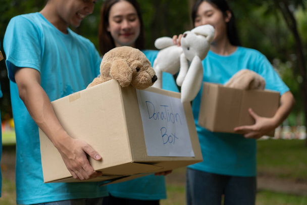Jovens estudantes asiáticos felizes diversos voluntários realizar doar caixa e brinquedos para caridade para compartilhar crianças e orfanatos, uma instituição de caridade para a sustentabilidade. Vida de trabalho voluntário e cooperação social - Foto, Imagem
