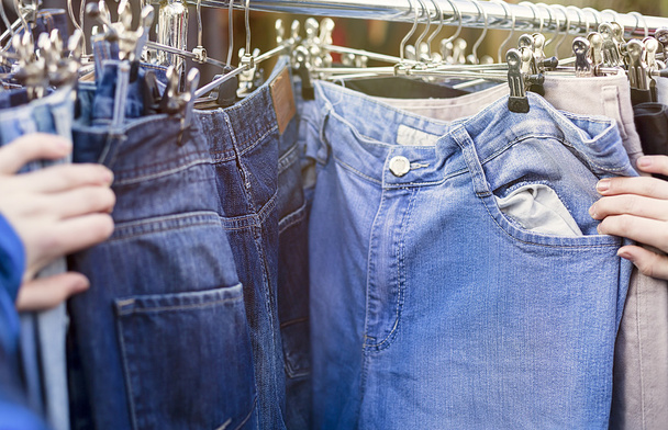 Close up van handen, op zoek naar broeken, jeans op een vlooienmarkt - Foto, afbeelding