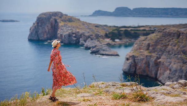 Miła, szczęśliwa kobieta, ciesząca się słonecznym dniem na greckich wyspach. Podróż do Grecji, wysp śródziemnomorskich poza sezonem turystycznym. Ciesząc się życiem i patrząc na morze. Turkusowe tło morskie. - Zdjęcie, obraz