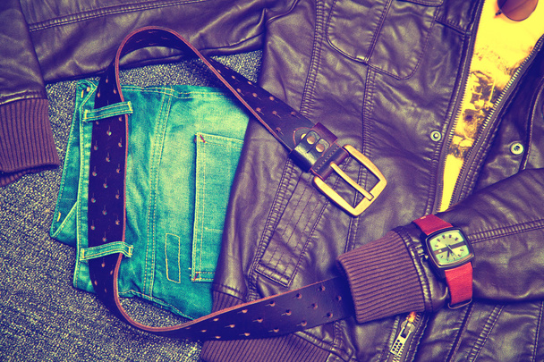 Kleding en accessoires: blue jeans met een lederen gordel, leren jas, T-shirt, horloges - Foto, afbeelding