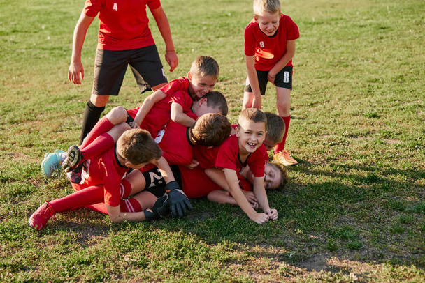 Забавные детские футбольные игроки команды на футбольном поле, трава на матче в движении радуются после того, как бомбардир забил гол. Играю в футбол. Концепция спортивного образа жизни, хобби, досуга. Объявление. - Фото, изображение