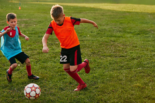 Jongens die dribbelen in sportuniform in teamtrui en schoenen. Kinderen voetballen op het voetbalveld. Kindervoetbalteam van de school. Concept van sport, gezonde levensstijl, activiteit, hobby. ad - Foto, afbeelding