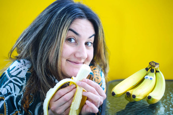smějící se žena jíst banán, žluté pozadí - Fotografie, Obrázek