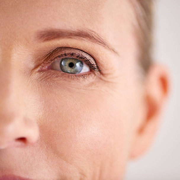 Βελτιώστε και διατηρήστε το δέρμα στο οποίο βρίσκεστε. Κοντινό πλάνο μιας ελκυστικής ώριμης γυναίκας με επίκεντρο τα μάτια της - Φωτογραφία, εικόνα