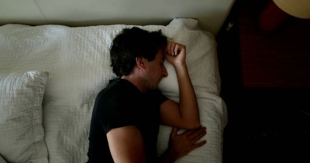 Young man lying down in bed falling asleep in afternoon nap - Photo, image