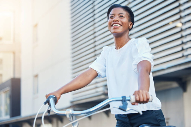 Feliz, ciudad y una mujer negra con una bicicleta para viajar, diversión de fin de semana o transporte sostenible. Sonríe, piensa y una joven africana con transporte o una bicicleta para un viaje neutral en carbono. - Foto, Imagen