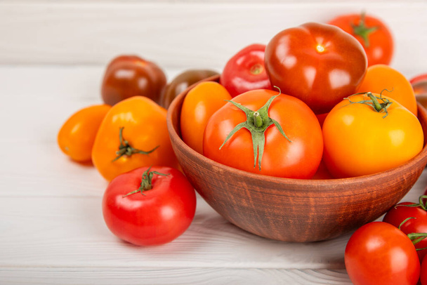 大理石のテクスチャの背景にトマト。チェリートマト、黄色、ピンク、茶色、黒のトマトをボウルに入れます。有機野菜、収穫。ビーガン。新鮮な熟したトマト。コピースペース. - 写真・画像