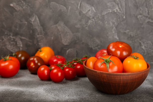 Tomaten op marmeren textuur achtergrond. Kerstomaten, gele, roze, bruine en zwarte tomaten in een kom. Biologische groenten, oogst.Veganistisch. Verse rijpe tomaten. kopieerruimte. - Foto, afbeelding