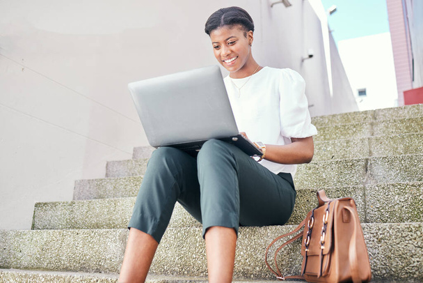 Woman, laptop and typing remote work on stairs with thinking, smile and ideas for content creation. African copywriting expert, computer and happy for vision, planning and solution for project. - Fotoğraf, Görsel