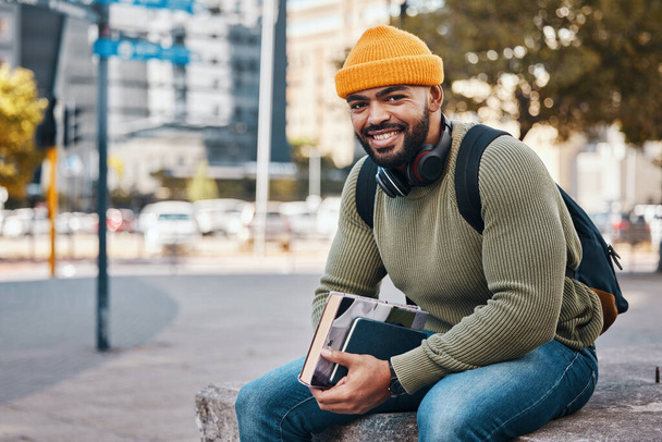 Porträt eines glücklichen Mannes in der Stadt, Universitätsbücher und Lächeln am Morgen entspannen auf dem Campus für Bildung mit Rucksack. Lernen, studieren und College-Student sitzt selbstbewusst auf städtischem Bürgersteig - Foto, Bild