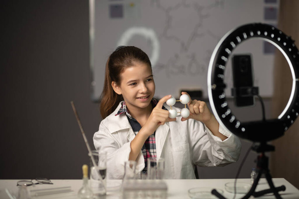 Tiede opiskelija kirjaa oppimisen blogi omistaa mallin molekyylirakenteen kameran älypuhelimen tekee kemiallisen kokeen laboratoriossa kotona. Nuori vaikuttaja kuvaamassa vlogia. Bloggaaminen - Valokuva, kuva
