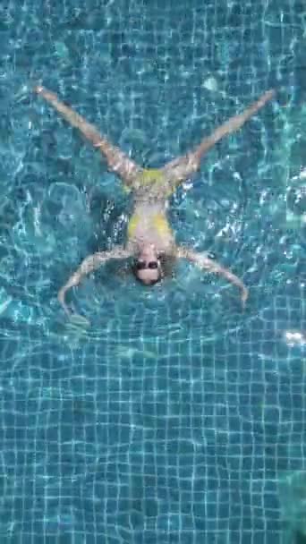 Top kilátás fiatal kaukázusi nő úszik a háton a medencében lassított felvételen. - Felvétel, videó