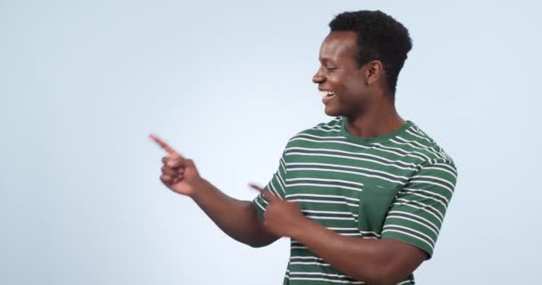 Black man, face and pointing to advertising in studio of information, deal and choice on blue background. Happy portrait, model and presentation of mockup, announcement and feedback of news about us. - Footage, Video