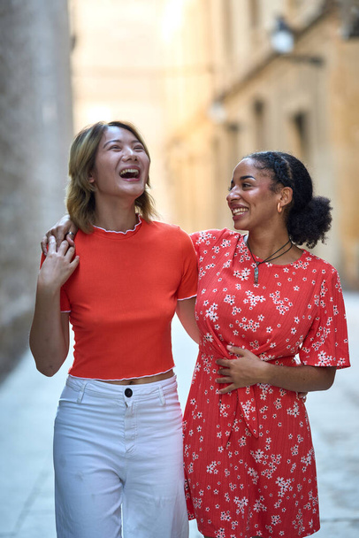 Retrato vertical de una feliz pareja de lesbianas abrazándose y riéndose en la calle de Barcelona - Foto, imagen