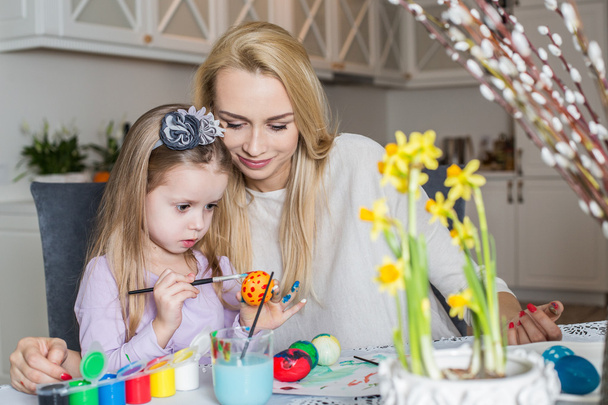 Loving mother and her daughter painting easter eggs - Fotoğraf, Görsel