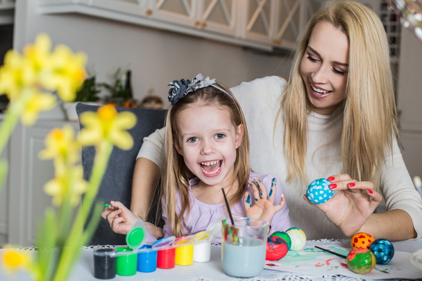 Happy mother and daughter painting easter eggs in the living room - Foto, Imagen