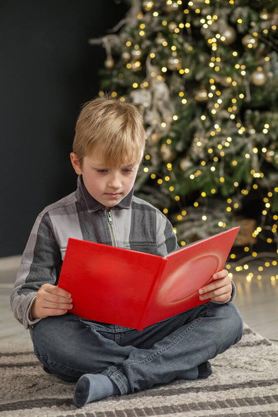 Lapsipoika avaa taikakirjan, lukee joulutarinoita ja satuja. Konsepti Uusi vuosi, Hyvää joulua, loma, loma, talvi, lapsuus. - Valokuva, kuva