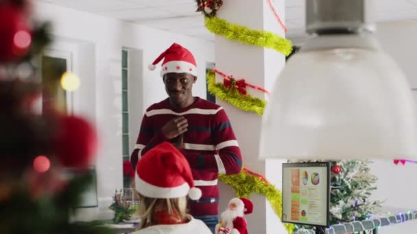 Африканський американський працівник носить різдвяний капелюх, розважаючи колег, імітуючи свого менеджера під час перерви. Команда компанії весело проводить пантоміму під час таємної вечірки Санта - Кадри, відео