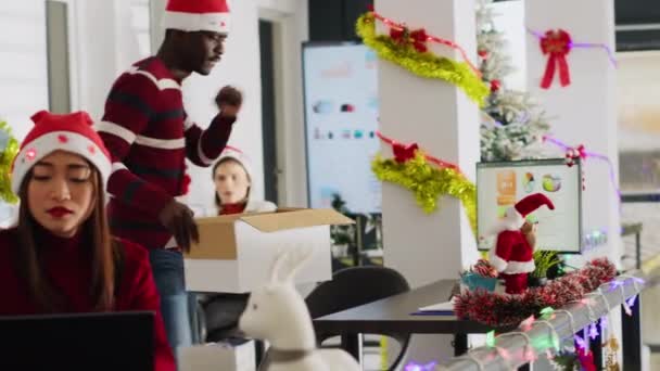 Щасливий афроамериканський працівник прибирає святкові прикрашені офісні столи перед від'їздом у відпустку. Працівник у Санта-капелюсі виходить на Різдвяні канікули, відчуваючи радість - Кадри, відео
