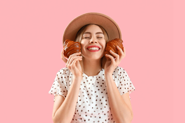 Mulher jovem feliz bonita em chapéu de vime com croissants saborosos no fundo rosa - Foto, Imagem
