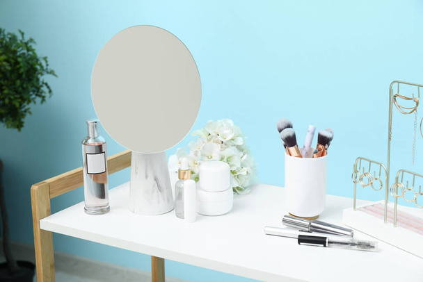 Diferentes cosméticos decorativos com espelho e jóias na mesa branca - Foto, Imagem