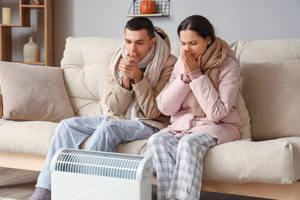 Frozen young couple warming near radiator at home - Photo, Image