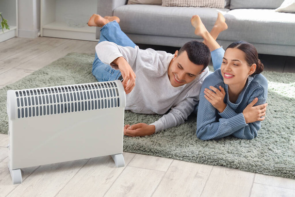 Jeune couple se réchauffant près du radiateur à la maison - Photo, image