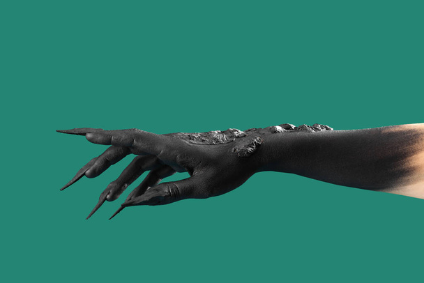 Μαύρο χέρι μάγισσας με νύχια σε πράσινο φόντο. Απόκριες γιορτή - Φωτογραφία, εικόνα