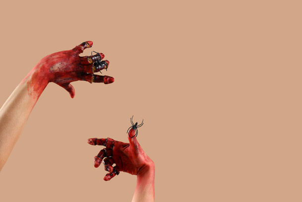 Кровавые руки зомби с пауками на бежевом фоне. Праздник Хэллоуина - Фото, изображение