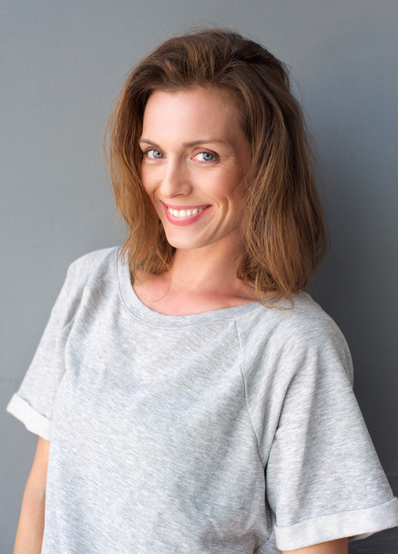 Retrato de uma bela mulher adulta média sorrindo no fundo cinza
 - Foto, Imagem