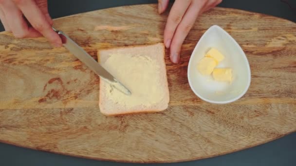 Manos femeninas extendiendo mantequilla sobre pan tostado en la cocina. Vista superior de la mesa de la cocina. Cocinar en la cocina - Imágenes, Vídeo