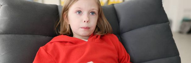 赤いパーカーの焦点を当てたティーンエイジャーの女の子は緊張した顔の表情を作るゲームコンソールを保持しています。子供は自宅近くで学校の後にビデオゲームをプレイ - 写真・画像