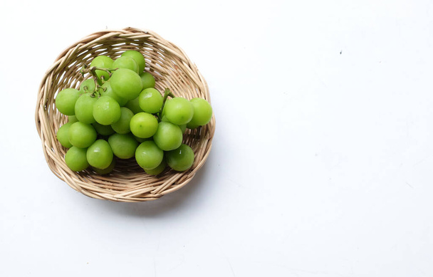 Bunch of fresh Sweet Green Shine Muscat (Vitis vinifera) grape and leaf in Bamboo basket isolate on a white backdrop .green grapes. Japanese grapes.Grapes green taste sweet growing natural - Photo, Image