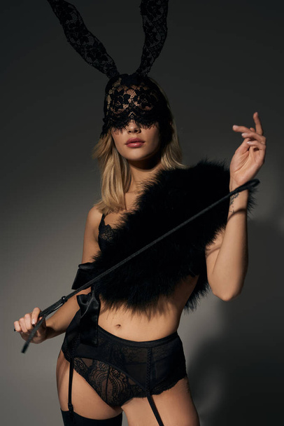 vertical shot of hot woman in sexy lace lingerie with rabbit mask and faux fur holding bdsm whip - Fotó, kép