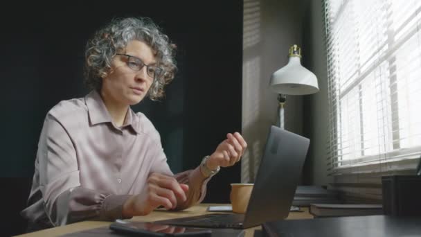 Starší běloška psycholožka nosí brýle sedí za stolem ve své kanceláři a konverzuje s pacientkou na videohovoru na notebooku - Záběry, video