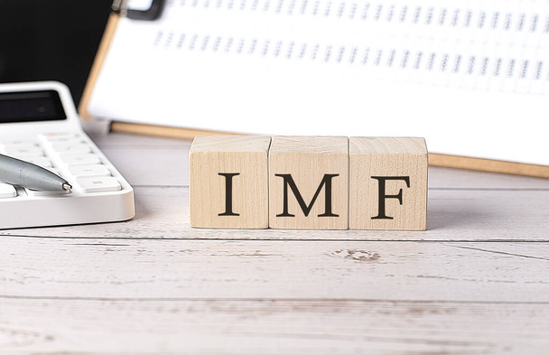 IMF word on wooden block with clipboard and calcuator - Photo, Image