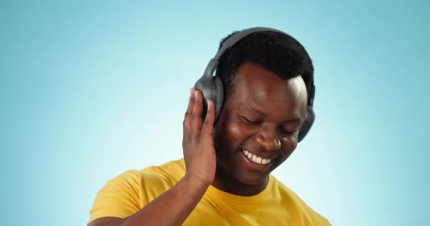 Ευτυχισμένος μαύρος, ακουστικά και χορός για podcast, μουσική ή playlist σε στούντιο ή μπλε φόντο. Αφρικανός άνδρας χαμογελά και απολαμβάνει audio streaming, τραγούδια ή sound track στο mockup. - Πλάνα, βίντεο