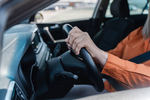 Επιλεκτική εστίαση στα γυναικεία χέρια του οδηγού στο τιμόνι κατά την οδήγηση του αυτοκινήτου. Οδική ασφάλεια. Σύγχρονοι άνθρωποι και μεταφορές έννοια. Αστικός τρόπος ζωής - Φωτογραφία, εικόνα