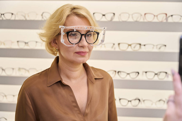 Consultant takes a photo of a woman wearing a trial frame, the salon has a wide selection of frames - Photo, Image