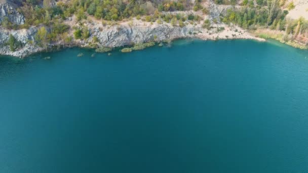 Top view of a flooded and abandoned granite quarry with clear turquoise water. Sunny autumn day. Drone (camera moves forward) - Footage, Video