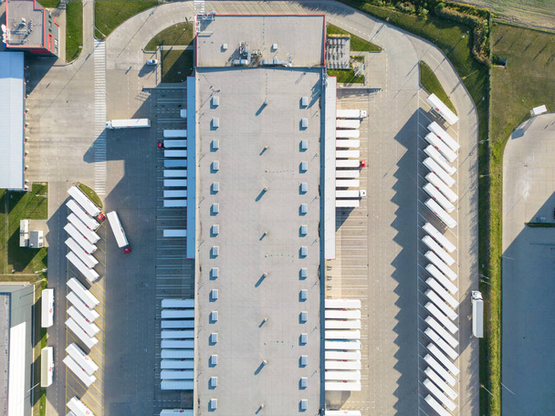 Malzeme deposunun havadan görüntüsü. Sanayi bölgesindeki lojistik merkezi yukarıdan. Lojistik merkez stok fotoğrafına yüklenen kamyonların hava görüntüsü - Fotoğraf, Görsel