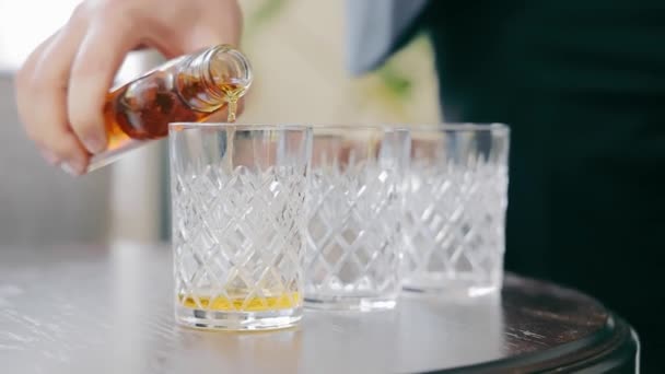 Bardağa viski döken bir adamın yakın çekimi. Masanın üzerinde viskinin döküldüğü üç cam bardak var.. - Video, Çekim