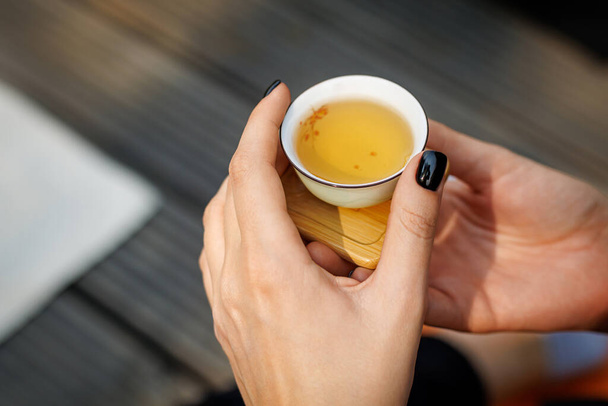 Malý čínský šálek čaje v rukou ženy během čajového obřadu - Fotografie, Obrázek