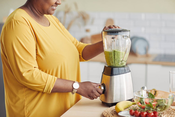Boční pohled detailní záběr černošky žena pomocí mixéru při výrobě zdravého smoothie v domácí kuchyni, kopírovat prostor - Fotografie, Obrázek