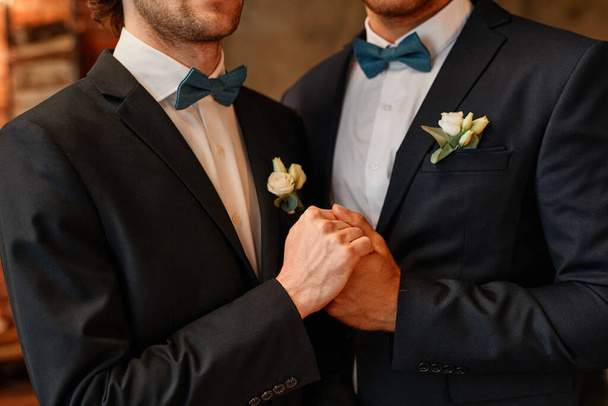 Κοντινό πλάνο του ανδρικού ομοφυλόφιλου ζευγαριού που κρατιέται χέρι-χέρι κατά τη διάρκεια της τελετής γάμου - Φωτογραφία, εικόνα