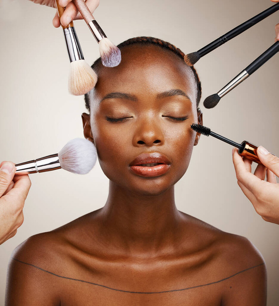 Μακιγιάζ, βούρτσες και μαύρη γυναίκα με καλλυντικά, περιποίηση δέρματος και δερματολογία σε γκρι φόντο στούντιο. Αφρικανός, ευεξία ή μοντέλο με εργαλεία, περιποίηση και περιποίηση με πολυτέλεια ή λάμψη με λάμψη. - Φωτογραφία, εικόνα