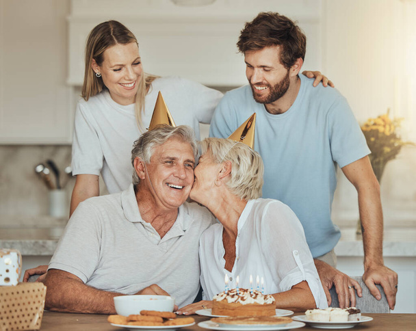 Joyeux anniversaire, baiser et parents aînés avec gâteau pour la fête, la célébration et l'événement festif à la maison. Famille, sourire et mère âgée, père et couple avec dessert, décoration et célébrer par amour. - Photo, image