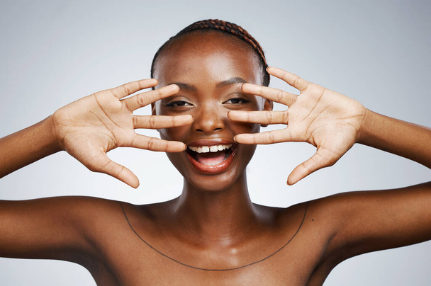Happy, hands and portrait of black woman for skincare, beauty reveal and excited on a studio background. Smile, young and an African person with a gesture for clean facial skin or a dermatology glow. - Fotografie, Obrázek