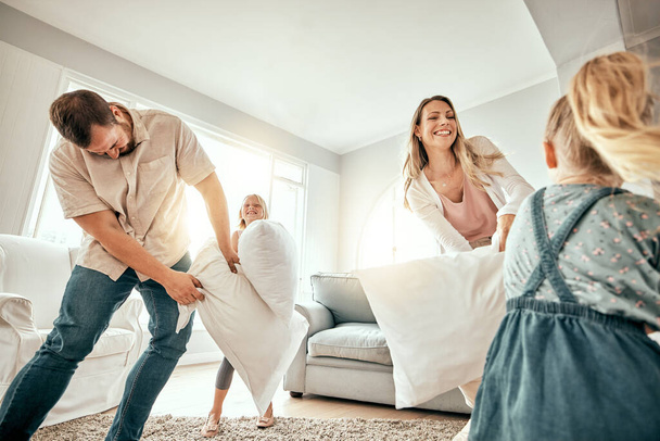 Happy family, pillow fight and playing in living room for fun bonding, holiday or weekend together at home. Mother, father and children smile with cushion game, play or free time for summer break. - Photo, Image